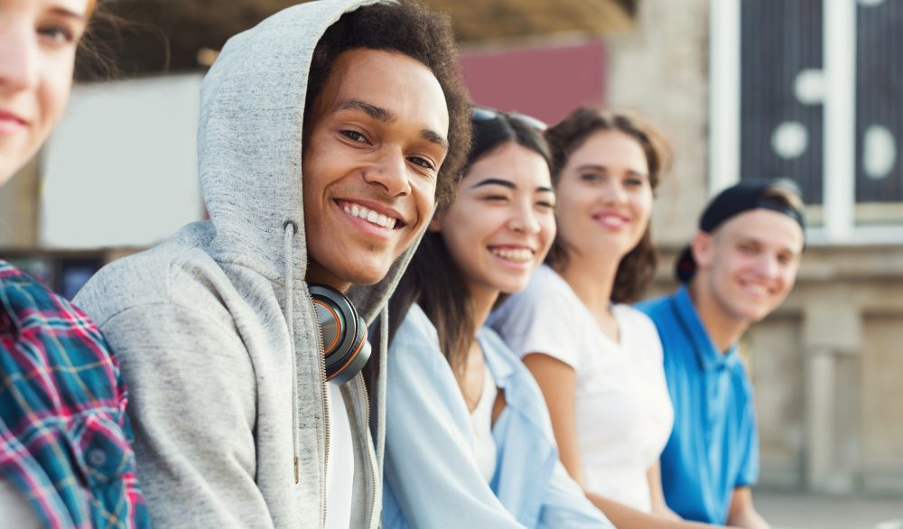 A group of teens are seated and smiling. 